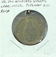 Front of circular bronze medal with image of Saint Benedict Joseph Labre and inscription