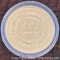 Obverse of brass New Hamburg Ontario 125th Anniversary trade dollar in capsule