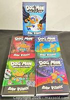Front covers of all five Dog Man hardcover books displayed upright