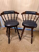 Two dark pine swivel barstools with navy upholstery, front angle view