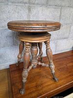 Full view of piano stool showing seat, legs and claw feet