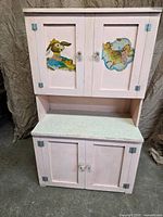 Full view of pale pink wooden play kitchen with double upper and lower doors and laminate counter
