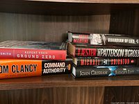 Stack of six hardcover books on shelf showing spines for identification