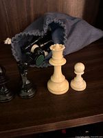 Bag tipped over showing plastic chess pieces in two colours and separate pieces displayed