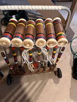 Wooden cart holding seven striped wooden mallets, wickets and accessories