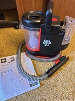 Overall view of Dirt Devil portable spot cleaner with hose, nozzle, tank, handle and manual