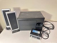 Subwoofer, two satellite speakers, control module with cables visible