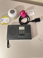 Front view of RadioShack DX-396 radio, two Bluetooth speakers, power adapter and leaflet on tabletop