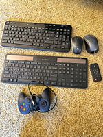 Group shot of both keyboards, two mice, gamepad, remote