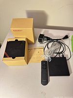 MeMoBOX device in open retail box with power adapter, HDMI cable, user guide and remote in view