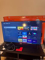 TV powered on displaying Roku home screen on stand