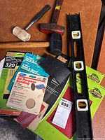 Group shot showing sledgehammer, rubber mallet, level and assorted sandpaper packs