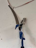 Close view of pruning head showing curved saw blade and rope mechanism