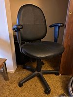 Front view of black faux leather office chair with armrests and 5-star base