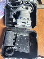 Finishing sander with accessories in open case