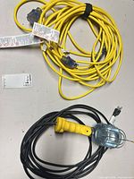 Shop light with black cord and two coiled yellow extension cords