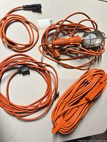 overview of work light and three orange extension cords on table