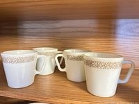 Four Corelle Woodland Brown mugs on shelf