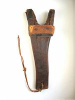 Full view of wooden boot jack hanging showing leather strap and forked end