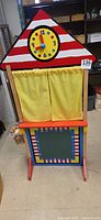 Front view of wooden puppet theater with yellow curtains and chalkboard panel