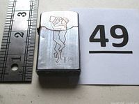 Front of Zenith Vietnam War lighter with engraving, ruler for scale and lot number