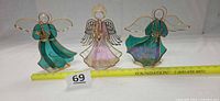 Full view of three stained glass angels with measuring tape for scale