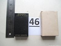 Black Zippo Lifetime Guarantee display case, plain cardboard sleeve, ruler for scale