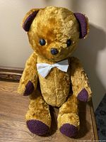 Full frontal view of teddy bear seated on wooden surface