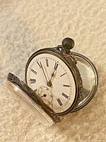 Side view of pocket watch open showing white enamel dial with Roman numerals and sub-seconds