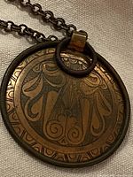 Front view of pendant showing engraved floral scroll pattern and coiled wire frame