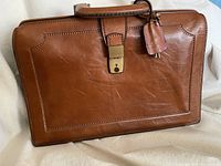 Front view of cognac leather Barantani briefcase with clasp and keys