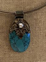 Front view of sterling silver snake chain necklace showing turquoise cabochon pendant with pearl accent