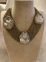 Full view of gold-tone collar necklace on display bust