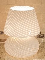 Lamp illuminated showing white translucent glass with diagonal swirl pattern and rounded stacked form