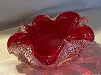 Top angled view showing ruby red center, clear rim with silver aventurine, ruffled edge