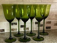 Front view of all six olive green goblets on countertop