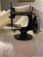 Left profile of Singer miniature sewing machine showing arm, base and crank