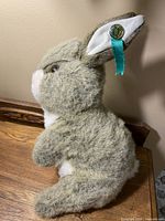 Side view of plush bunny hand puppet showing ribbon and anniversary pin