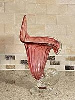 Full side view of cranberry to clear cornucopia vase showing ribbed body and ruffled rim