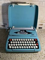 Typewriter inside open hard case showing full keyboard and carriage