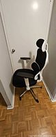 Side view showing black seat, mesh back, white frame, adjustable arm, headrest, base with casters