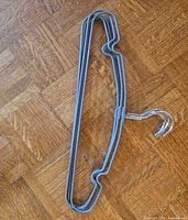 Two gray coated metal hangers nested together on wood floor