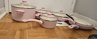 Full set of pink cookware displayed on floor