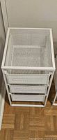 Front angled view of one white metal mesh 3-drawer unit