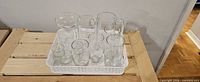 Basket containing clear glass pitcher, carafe, assorted tall, medium and small glasses