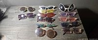 All twelve pairs of assorted sunglasses laid out on tabletop