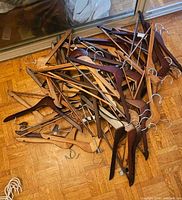 Pile of roughly 50 wooden hangers in assorted wood tones with metal hooks