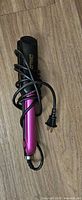 Full view of metallic pink flat iron with cord and plug visible