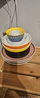 Stack of six mixed ceramic plates and bowls showing colours and patterns