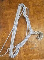 Bundle of pastel rubber-coated metal wire hangers with chrome hooks on wood floor